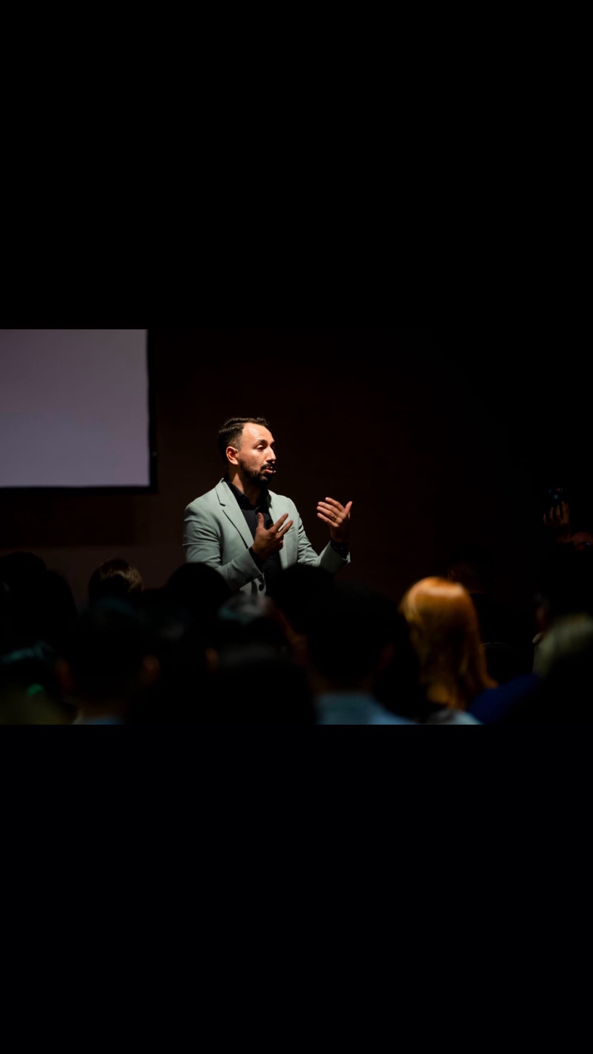 Yehan Echenique dando una conferencia con saco claro frente al público